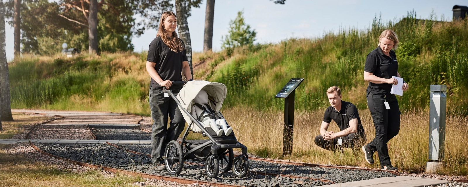 Женщина идет по каменистой местности с четырехколесной коляской Thule Urban Glide, чтобы проверить ее устойчивость, в то время как двое других внимательно наблюдают.